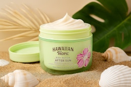 a green jar of body butter on a beach 