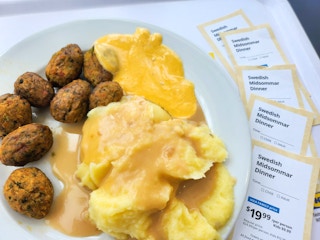 A plate of food from Ikea next to tickets for the Ikea Swedish Midsommar Dinner