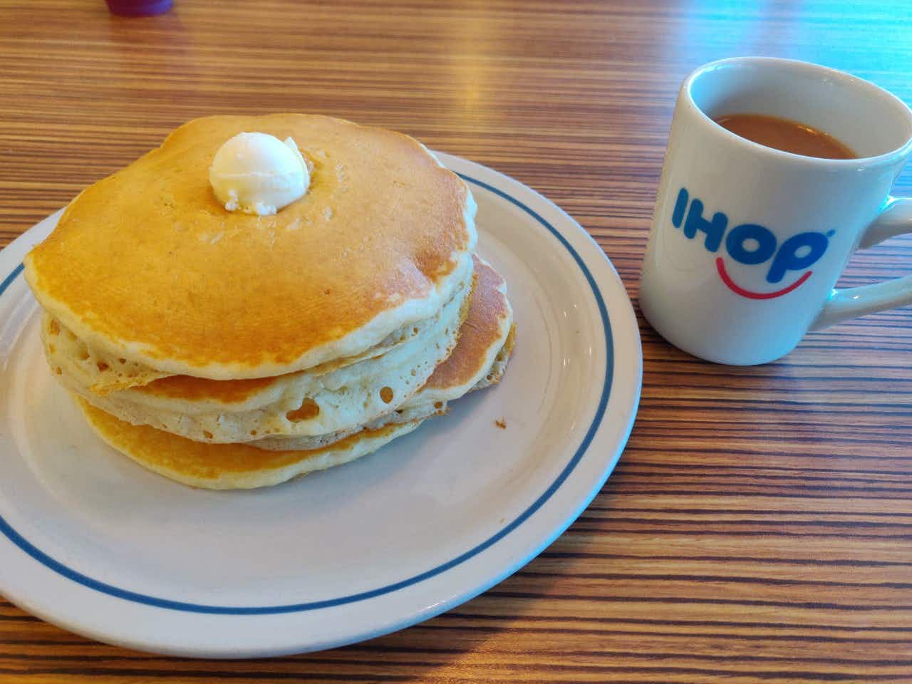 ihops full stack of pancakes next to a cup of coffee