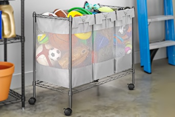Lifestyle image of the Whitmor 3-Bag rolling organizer sorter used in garage to store outdoor toys