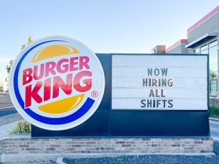 a large outside burger king sign with hiring all shifts sign