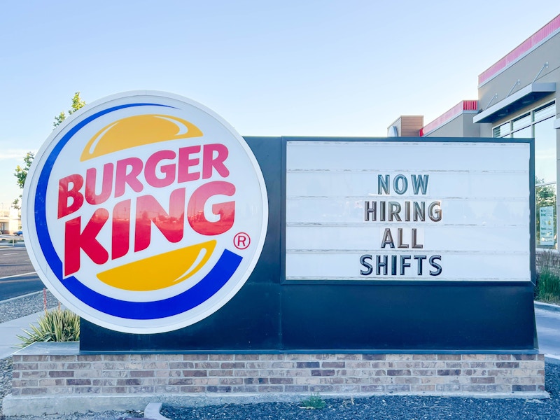 a large outside burger king sign with hiring all shifts sign