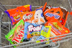 bags of candy in a cart including reese's, twix, trolli, kit kat, and snickers