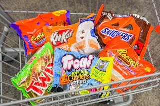 bags of candy in a cart including reese's, twix, trolli, kit kat, and snickers