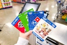 person holding steak n shake, xbox, dominos, and coldstone gift cards near a checkout counter