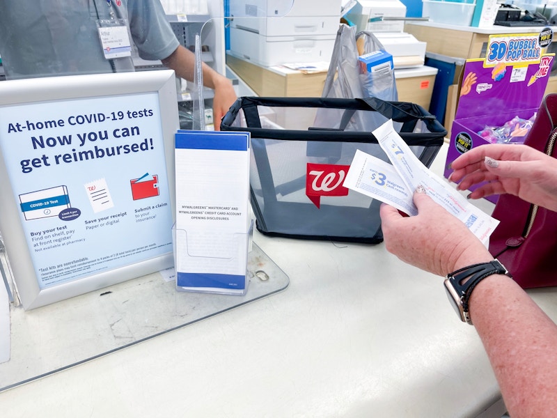 someone holding coupons in front of walgreens register