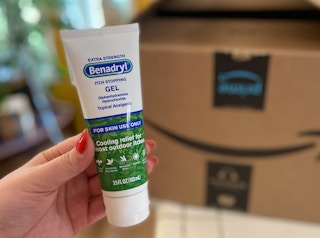 hand holding benadryl anti-itch gel cream in front of an amazon box