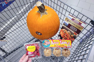 raspberries, caramel apples, schnitzel, and a pumpkin in a cart