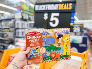 a hand holding a Melissa & Doug chunky puzzle in front of a $5 sign
