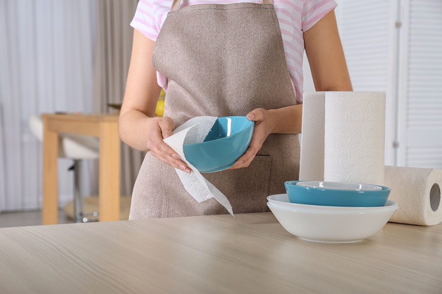 Person drying dishes with a paper towel