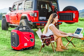 Lifestyle image of woman using a PowerSmart Gas Generator to power her laptop outdoors