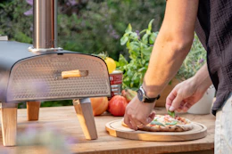 a man making a pizza outside