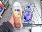 hand holding softsoap body wash and hand soap refill in walgreens cart
