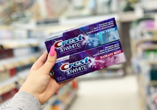 hand holding two boxes of Crest 3D White toothpaste