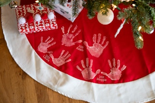 A Tree Skirt with white hand prints on it.