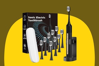 A black sonic electric toothbrush sits in its charger. Next to it are 9 extra heads, a carrying case, and the box.