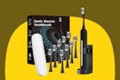 A black sonic electric toothbrush sits in its charger. Next to it are 9 extra heads, a carrying case, and the box.