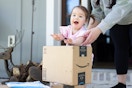 An image of a baby girl standing close to an Amazon box