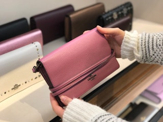woman holding a small pink coach shoulder bag in the coach store