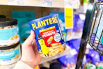 person holding a jar of planters peanuts in front of the shelf