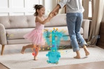 parent and child dancing around giraffe toy