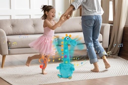 parent and child dancing around giraffe toy