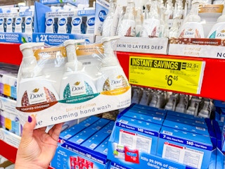 person holding a set of dove hand soaps by a sign for $6.46