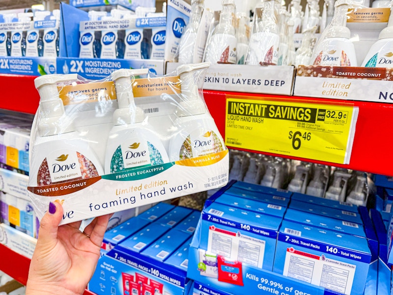 person holding a set of dove hand soaps by a sign for $6.46