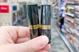 person holding 2 revlon lipsticks in an aisle