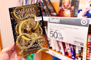 Sarah J. Mass Book: House of Flame and Shadow held in front of Target BOGO 50% off sale sign