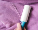 a person using a lint roller on a purple hoodie