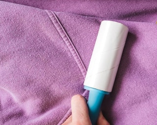 a person using a lint roller on a purple hoodie