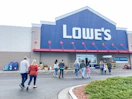 A group of people walking into a Lowe's store.