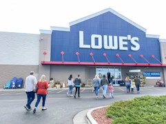 A group of people walking into a Lowe's store.