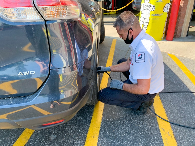 person putting air into vehicle tires at costco