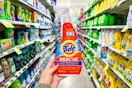 a hand holding a bottle of stain remover in a store's aisle