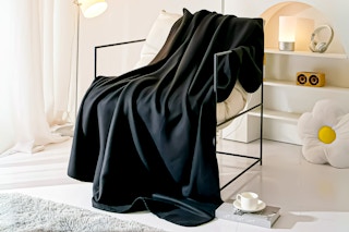 Lifestyle image of a black Mainstays Fleece Blanket draped over a chair in a room