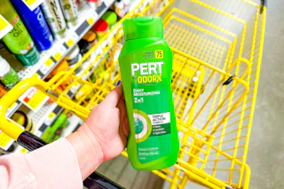 hand holdling a bottle of pert plus shampoo over yellow shopping cart
