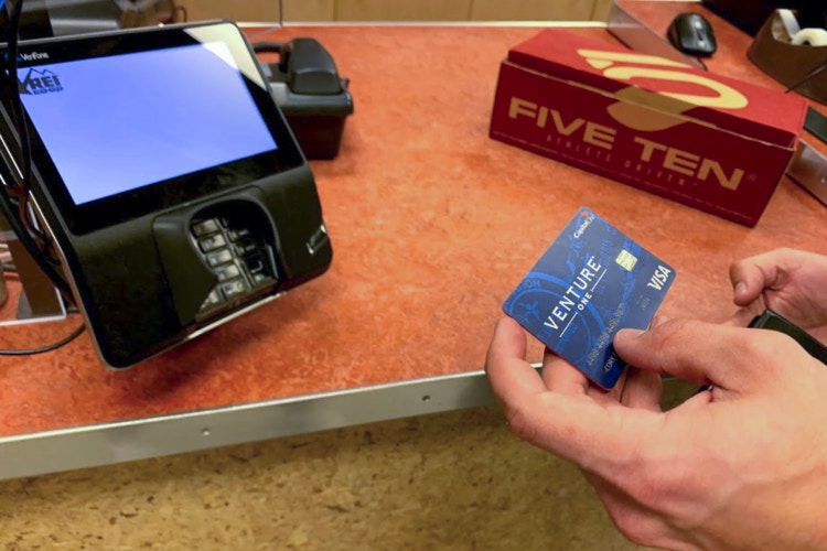 Man reading the last 4 digits on his credit card to return shoes at REI