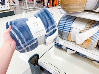 hand holding a threshold faux sherling throw blanket in front of target shelf