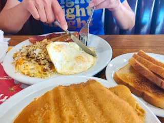 a person cutting their food up at dennys
