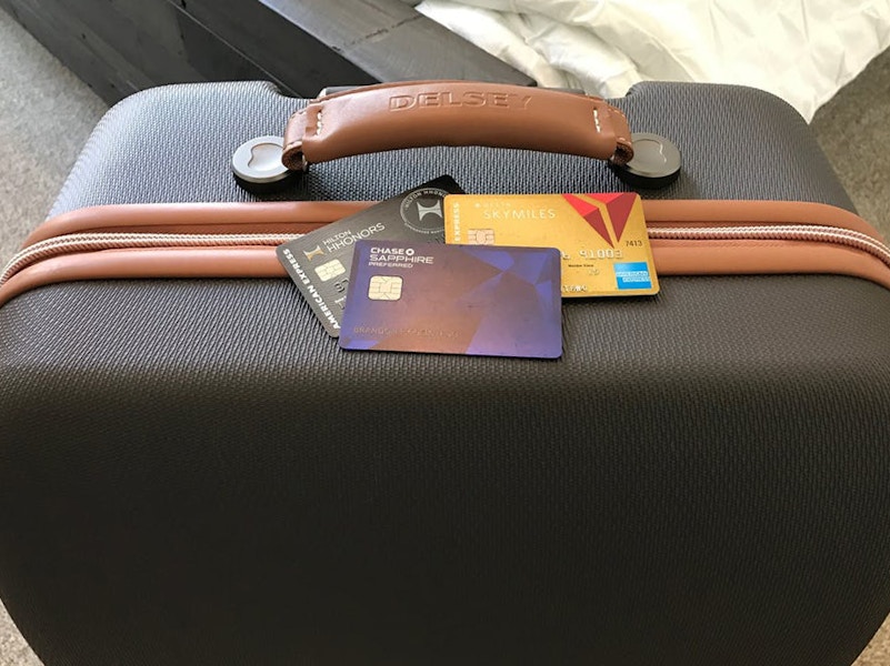 Travel credit cards sitting on top of a suitcase.