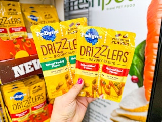 hand holding two pedigree drizzlers in walmart aisle