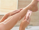 a person shaving their legs with a pink razor