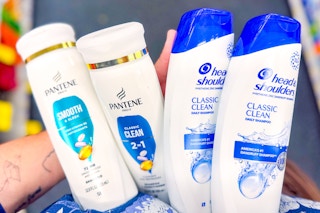 person holding pantene and head & shoulders shampoo bottles