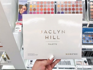 hand holding Morphe eyeshadow palette in front of Target aisle