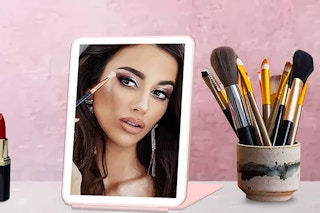 A woman doing her makeup in a mirro