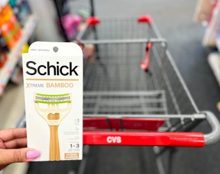 hand holding pack of Schick Xtreme Bamboo razor in front of shopping cart