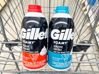 A couple cans of Gillette shaving cream sitting in a store cart.