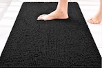 Lifestyle image of the Smiry Chenille Bathroom rug in the color black being stepped on
